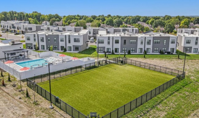 A perfect fit for the whole family a large green field with buildings in the background