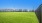 a large green field with buildings in the background